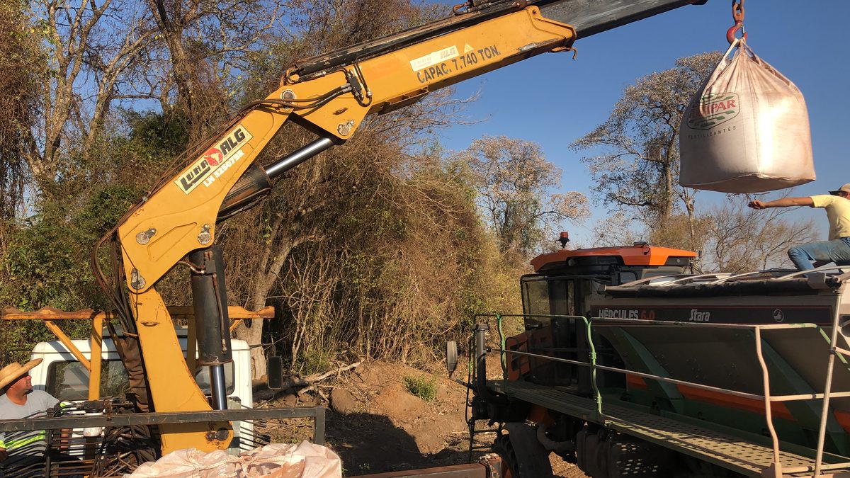 Munck erguendo big bag de fertilizante para o distribuidor Hércules no talhão